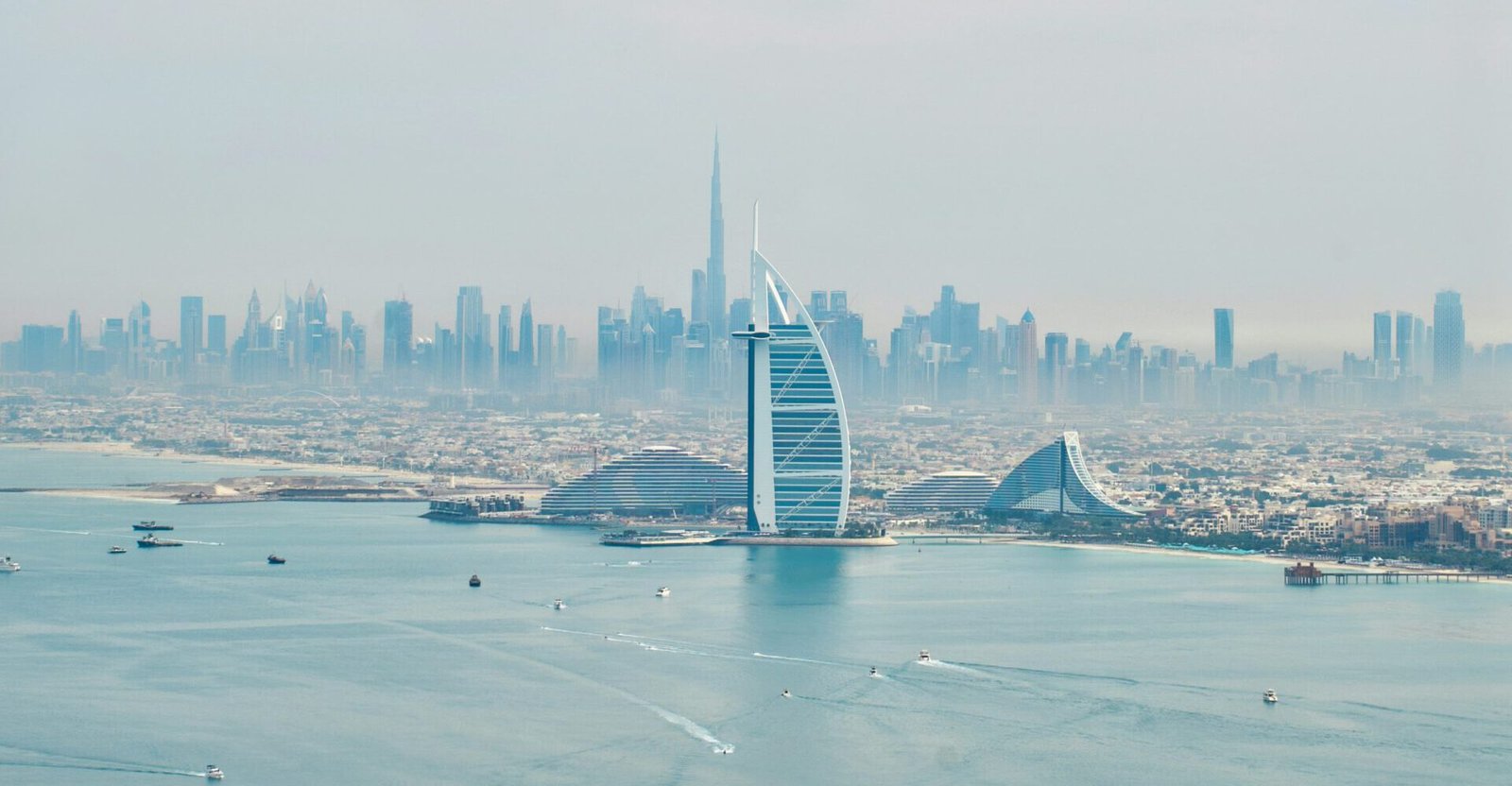 Eine Aufnahme von Dubai mit dem Burj Al-Arab im Vordergrund und Burj Khalifa im Hintergrund.