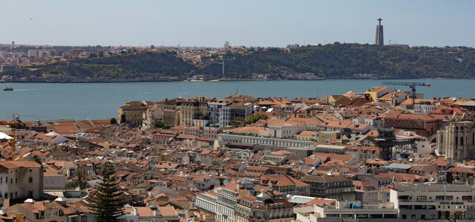 Eine Panoramaufnahme von Lissabon mit dem Denkmal Cristo Rei im Hintergrund
